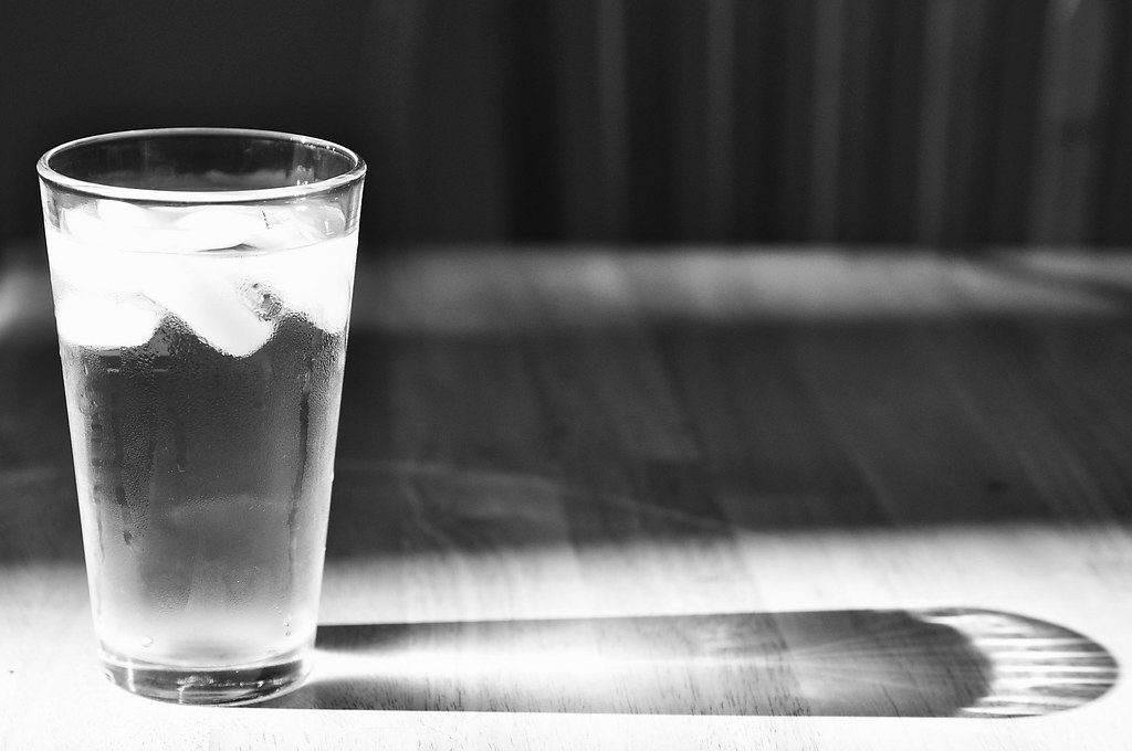 Un verre d'eau posé sur une table à la lumière naturelle