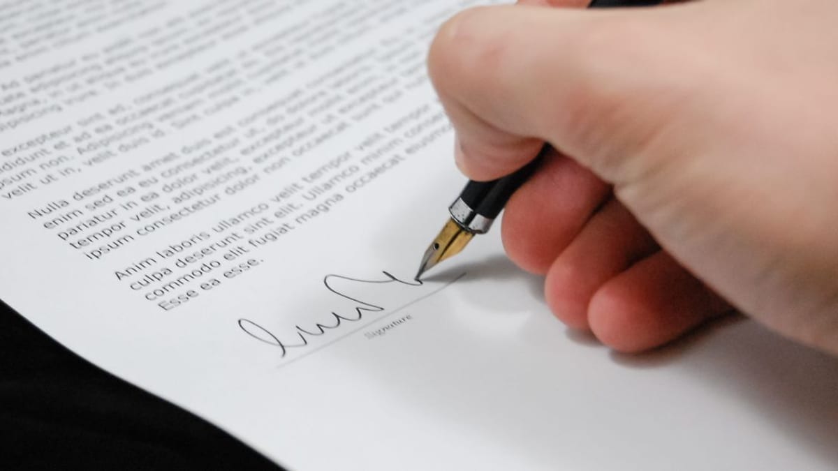 A hand signing a printed document