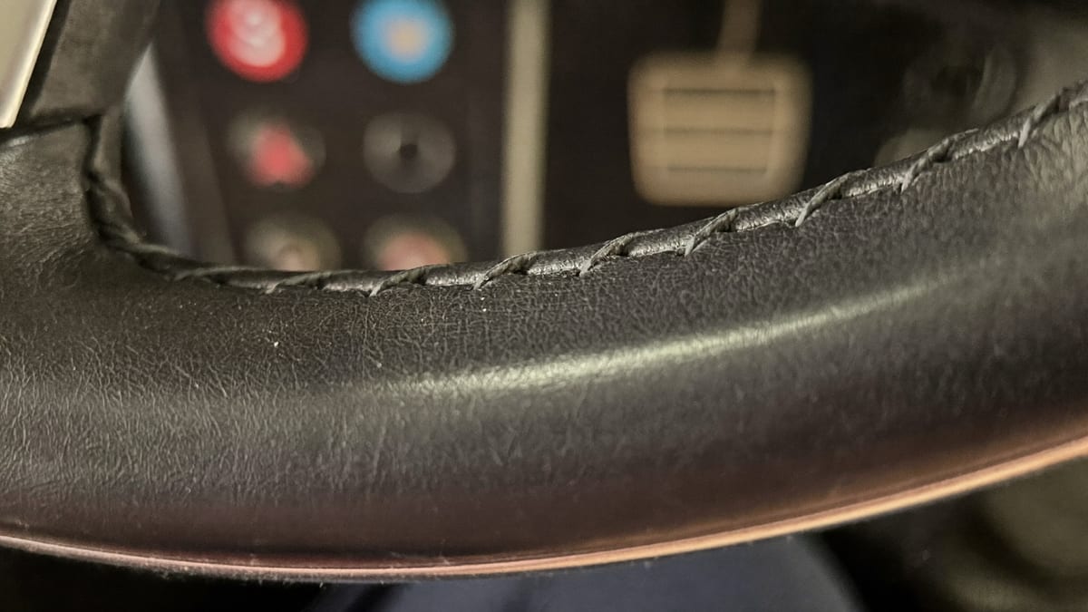 Close-up of the stitched leather rim of a steering wheel