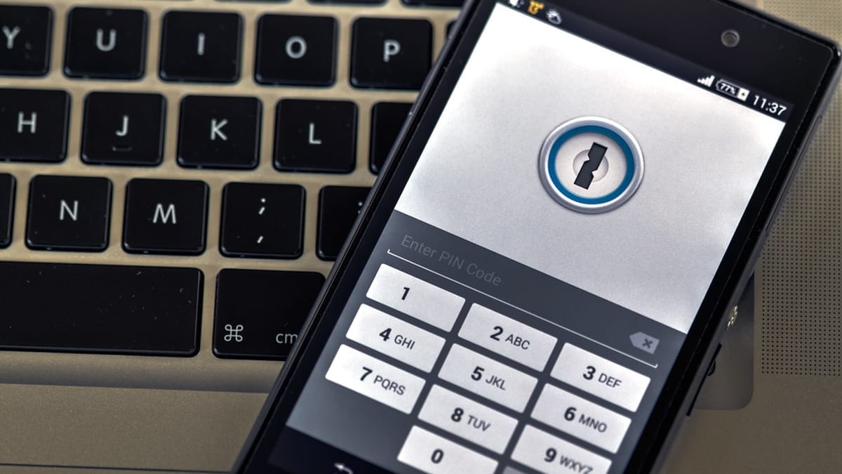 A phone showing a PIN entry screen resting on a laptop keyboard