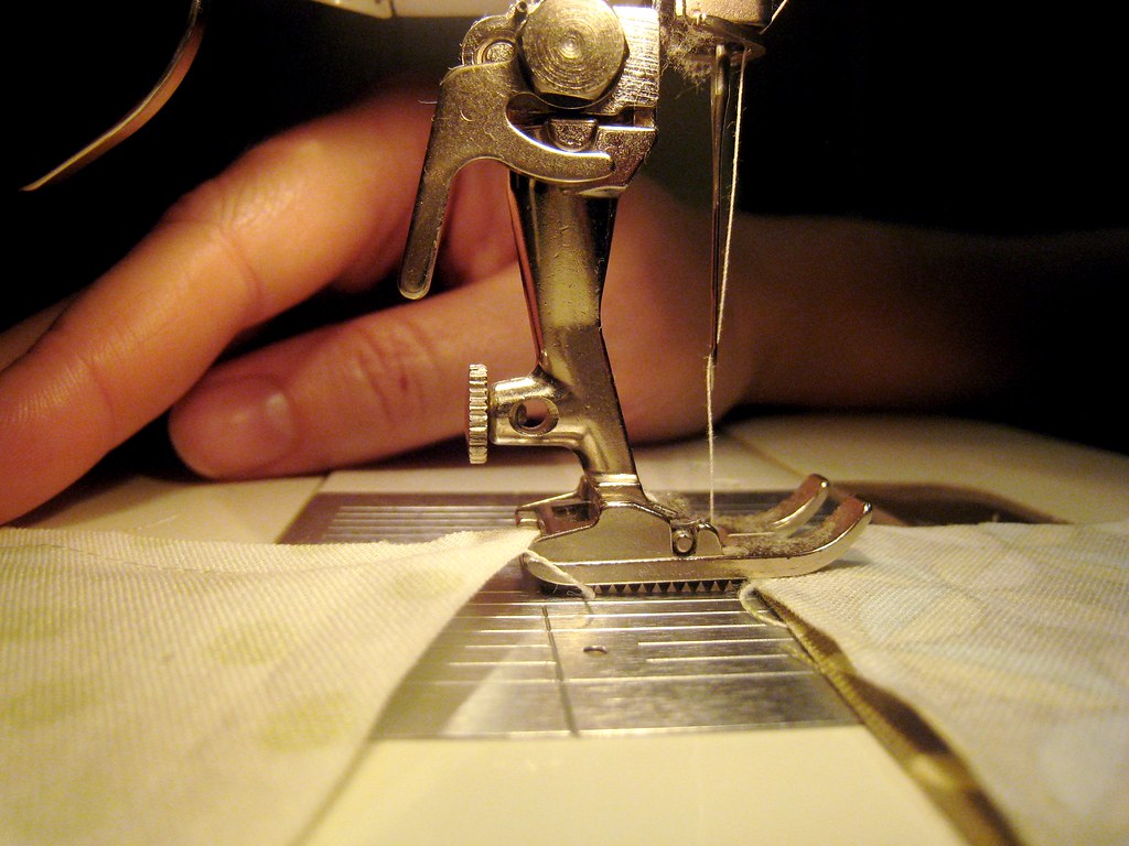 A yarn needle and thread beside crochet work