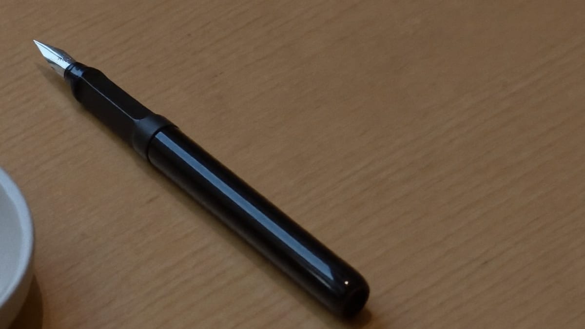 A plain desk with a pen and an empty notepad in daylight