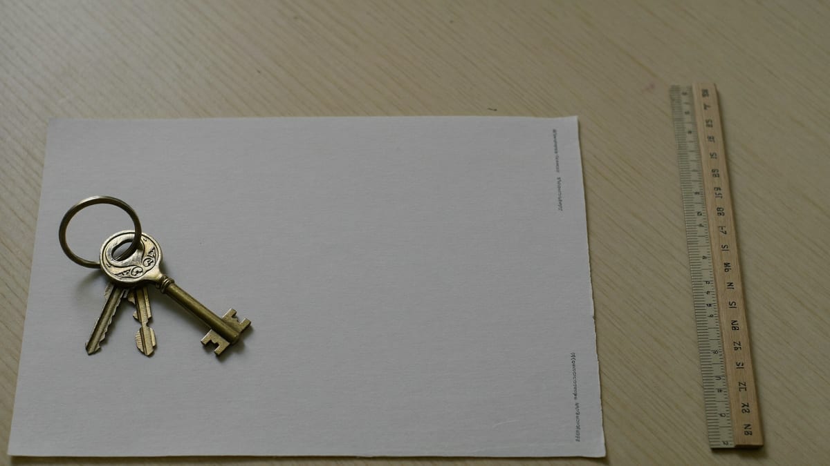 A set of brass house keys resting on a blank sheet of paper