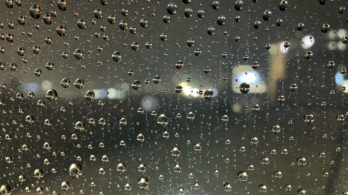 Rain running down a dark window at night