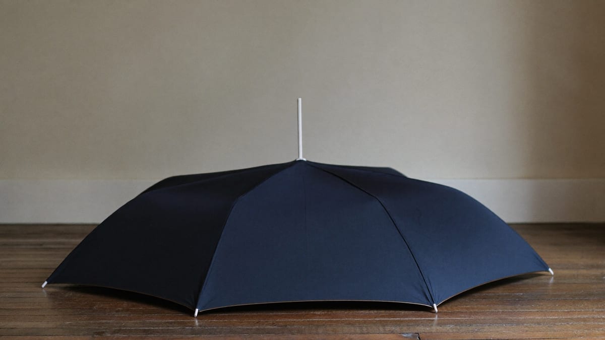 A closed umbrella leaning against a wall